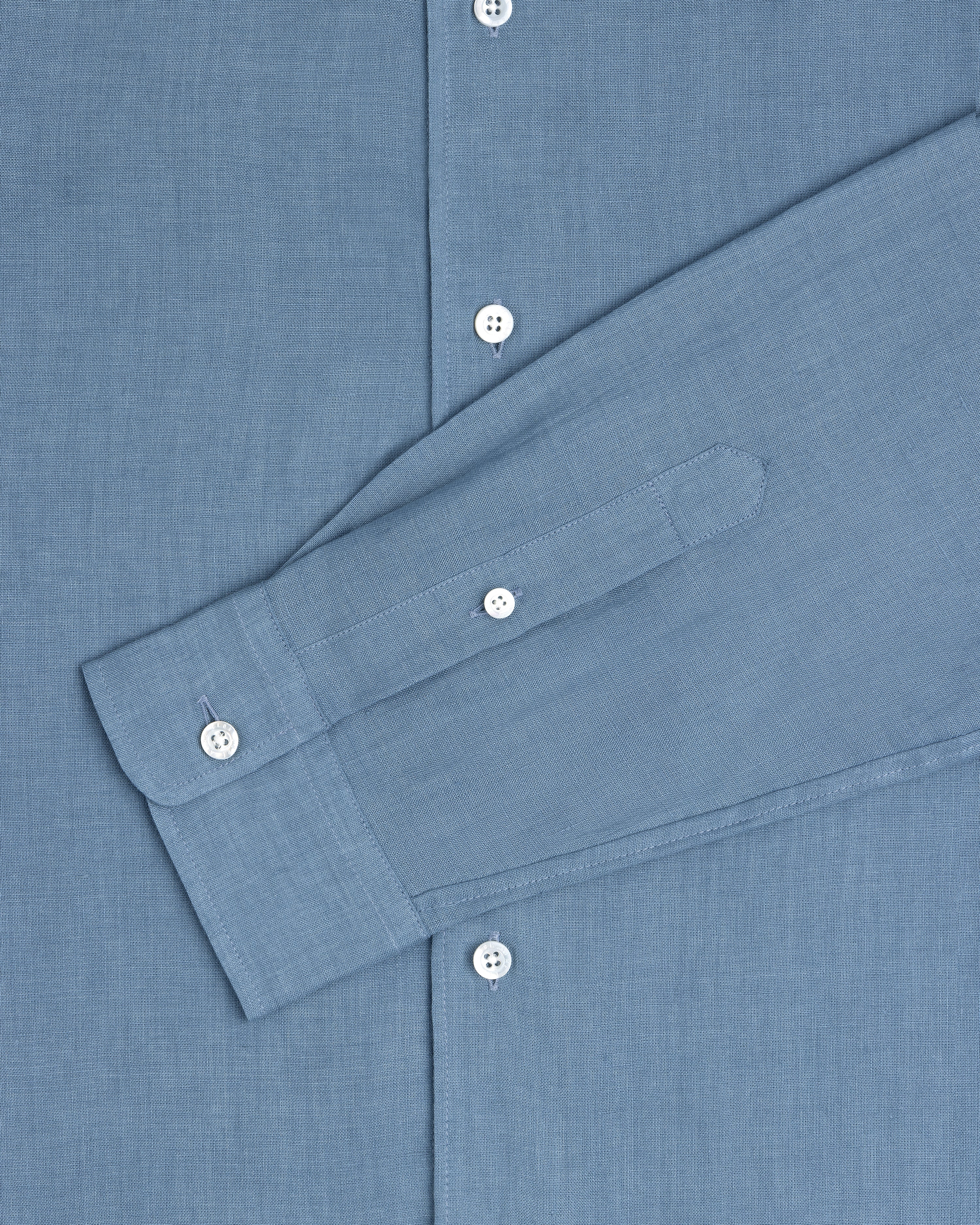 The Long-Sleeve Linen Shirt in blue features white buttons and is shown from chest to cuff.