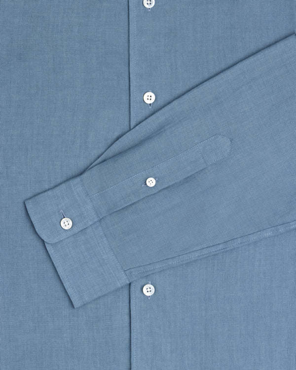 The Long-Sleeve Linen Shirt in blue features white buttons and is shown from chest to cuff.
