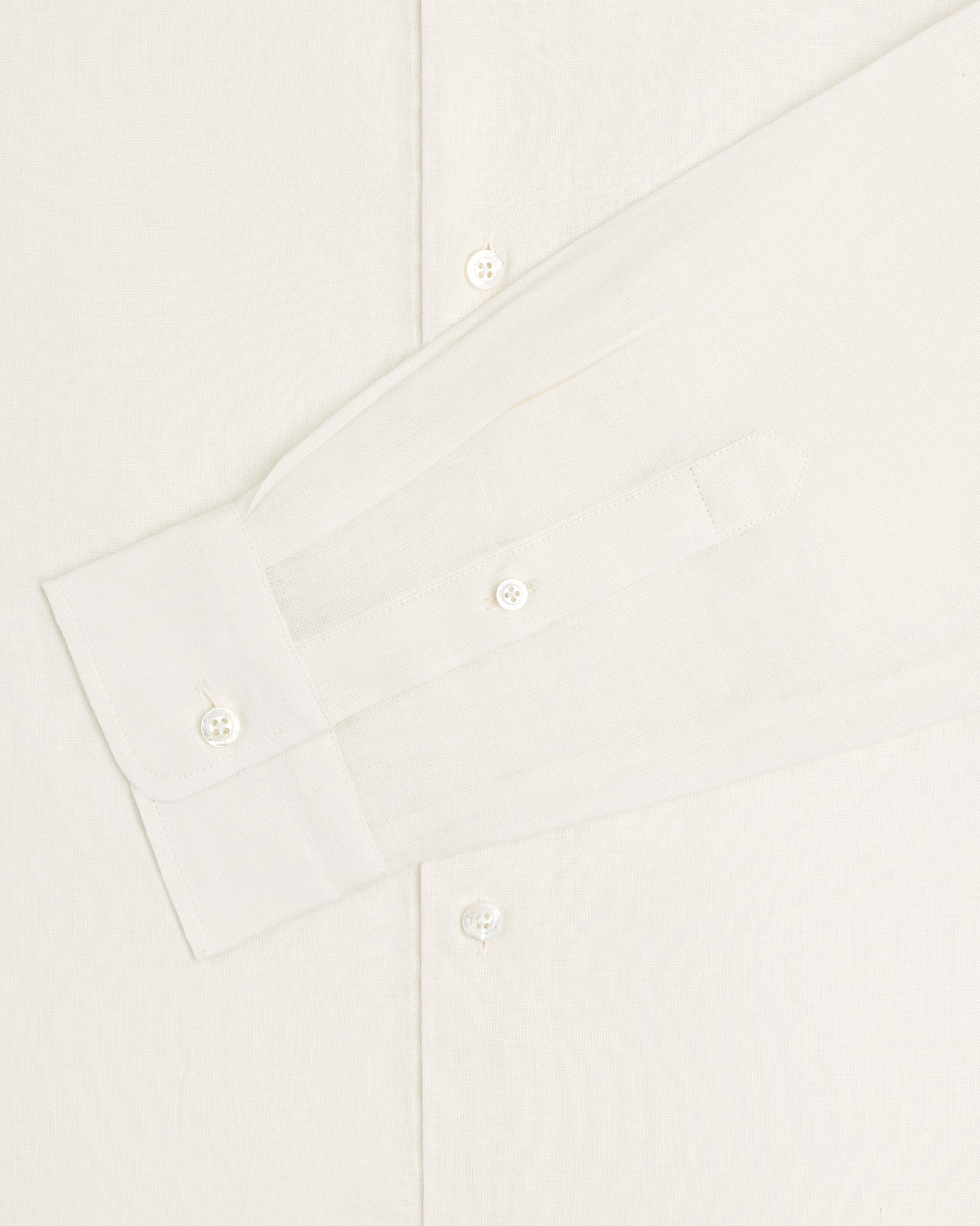 A close-up of the Long-Sleeve Linen Shirt displays its sleeve, cuff, and buttons against a light background.