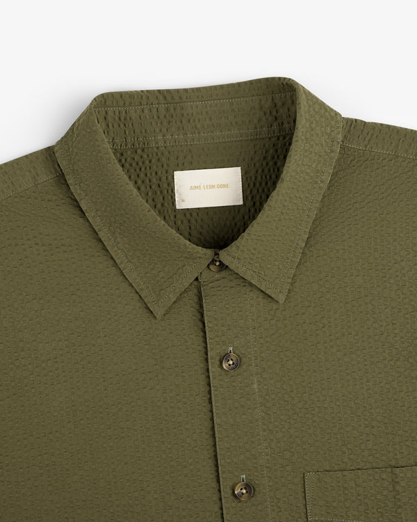 Olive green Short-Sleeve Seersucker Shirt with collar and chest pocket, shown from above.