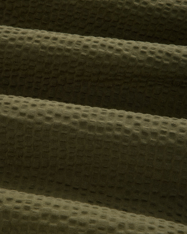 Close-up of Short-Sleeve Seersucker Shirt in olive green with a textured, waffle-like pattern and horizontal folds.