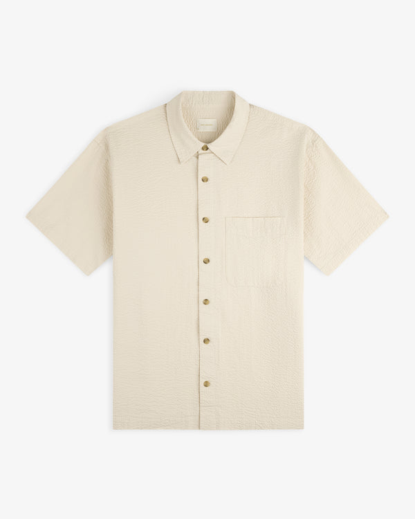 Short-Sleeve Seersucker Shirt in textured beige with front pocket, shown laid flat on a white background.