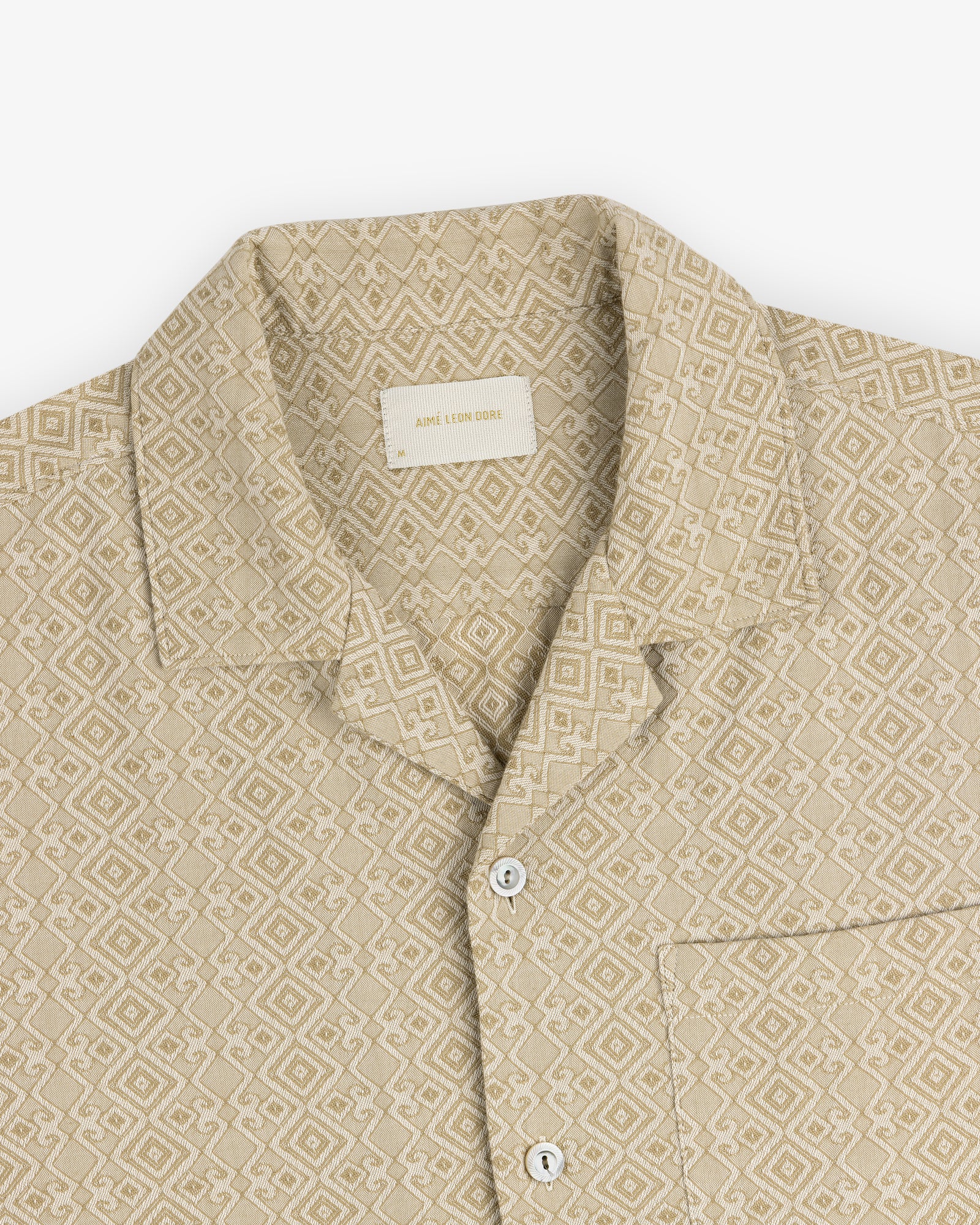 Jacquard Leisure Shirt—beige with geometric pattern, collar, chest pocket, and white buttons on a flat white background.