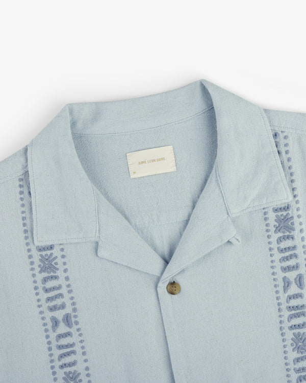 Linen Blend Leisure Shirt in light blue with a single brown button and geometric embroidery on the front edges.