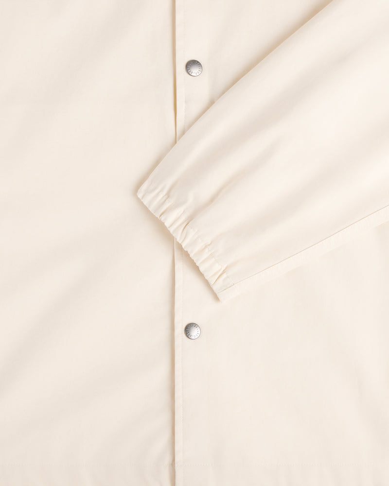 Close-up of the Marina Jacket in cream with silver snap buttons and elasticated sleeve cuffs.