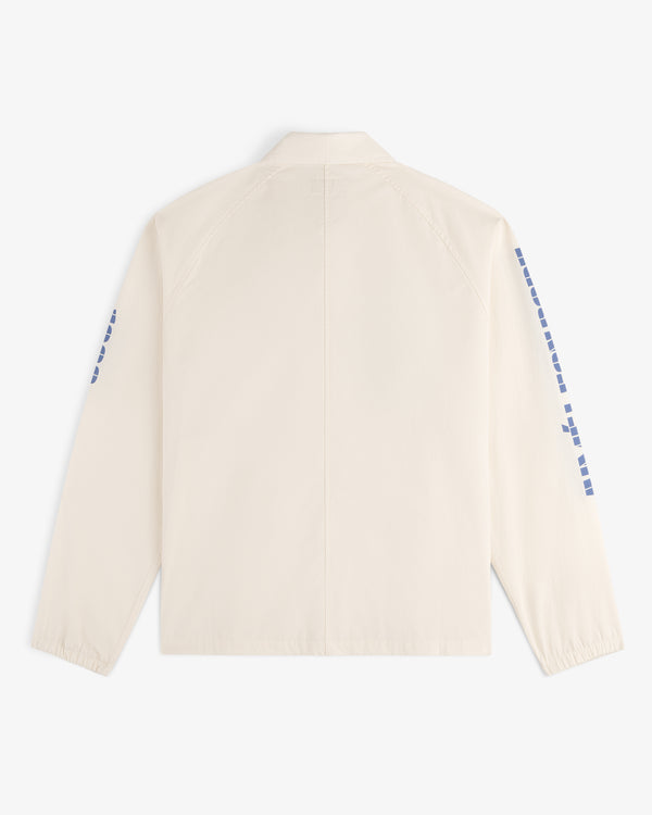 Back view of the Marina Jacket, a light beige long-sleeve with blue square designs on the sleeves.