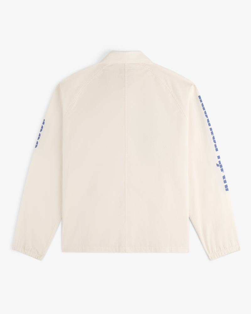 Back view of the Marina Jacket, a light beige long-sleeve with blue square designs on the sleeves.
