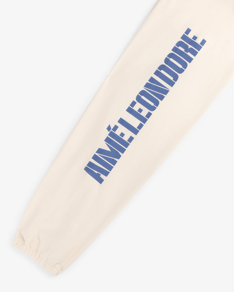 Cream-colored Marina Jacket sleeve with large blue AIMÉ LEON DORE print and an elastic cuff at the wrist.
