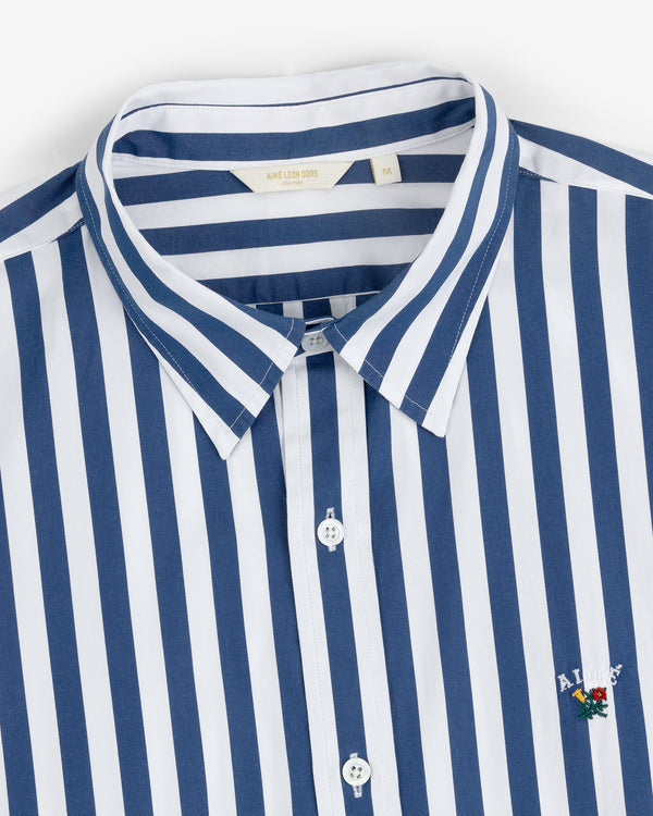 Striped Leon Overshirt: blue and white vertical stripes, collared, button front, small chest logo.
