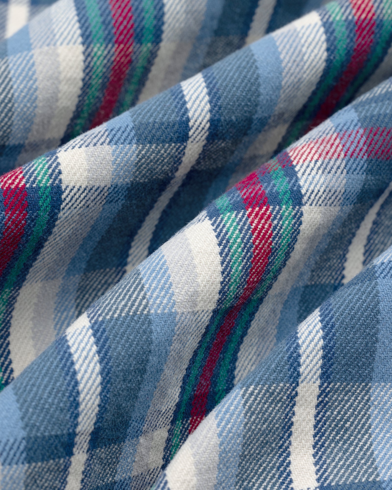 Close-up of Plaid Work Shirt fabric in blue, white, green, and red with soft folds and textured surface.