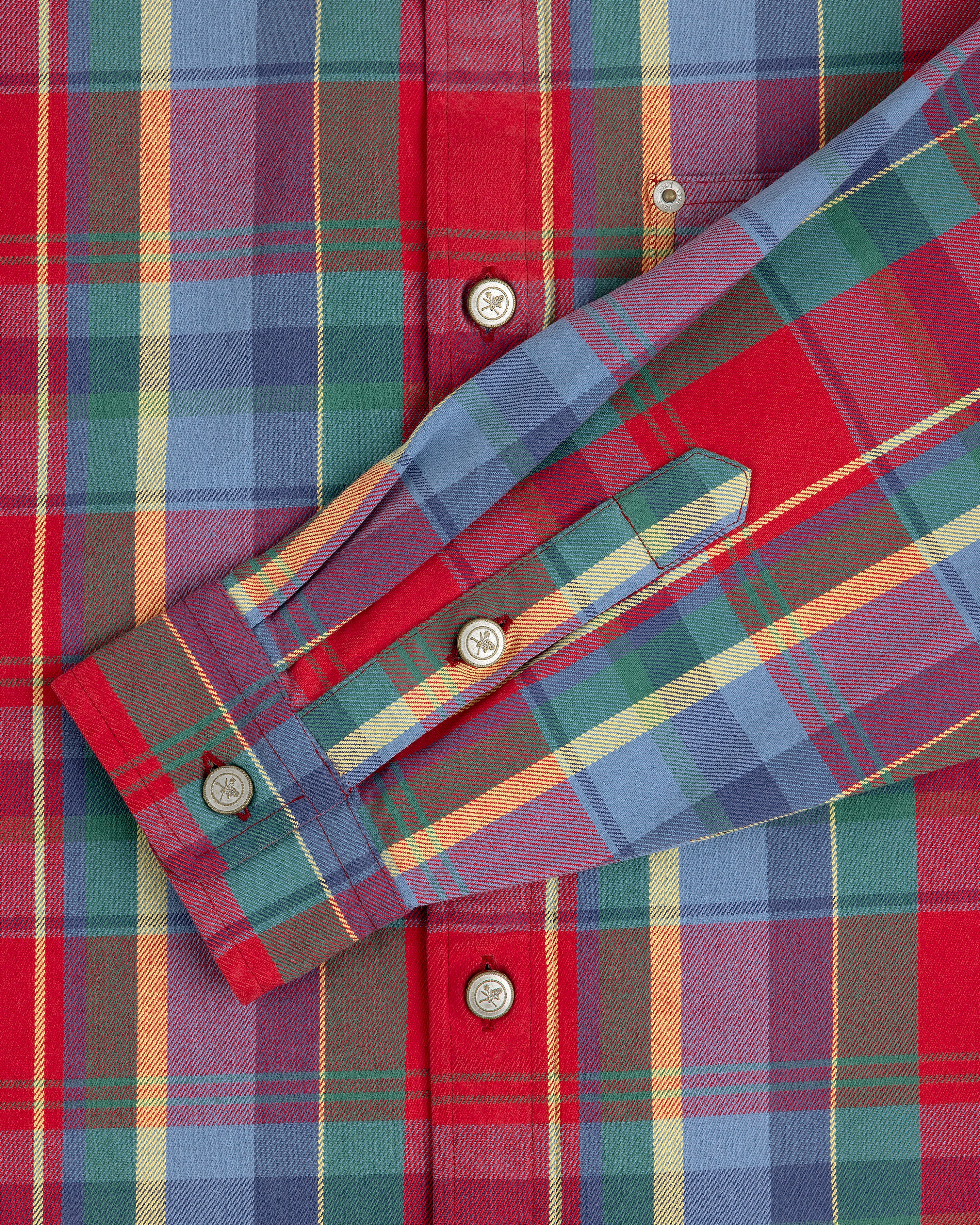 Close-up of Plaid Work Shirt in red, blue, green, and yellow with white buttons and a folded sleeve across the front.