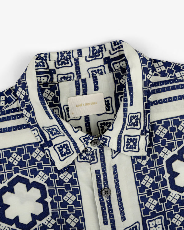 Close-up of the Mosaic Button Down Shirt with a blue and white geometric pattern and buttons, Aimé Leon Dore label inside.
