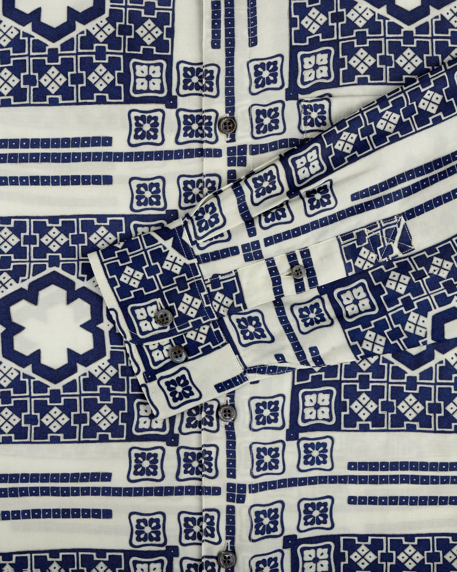 Close-up of the Mosaic Button Down Shirt with blue and white geometric patterns, buttons, and a folded cuff.