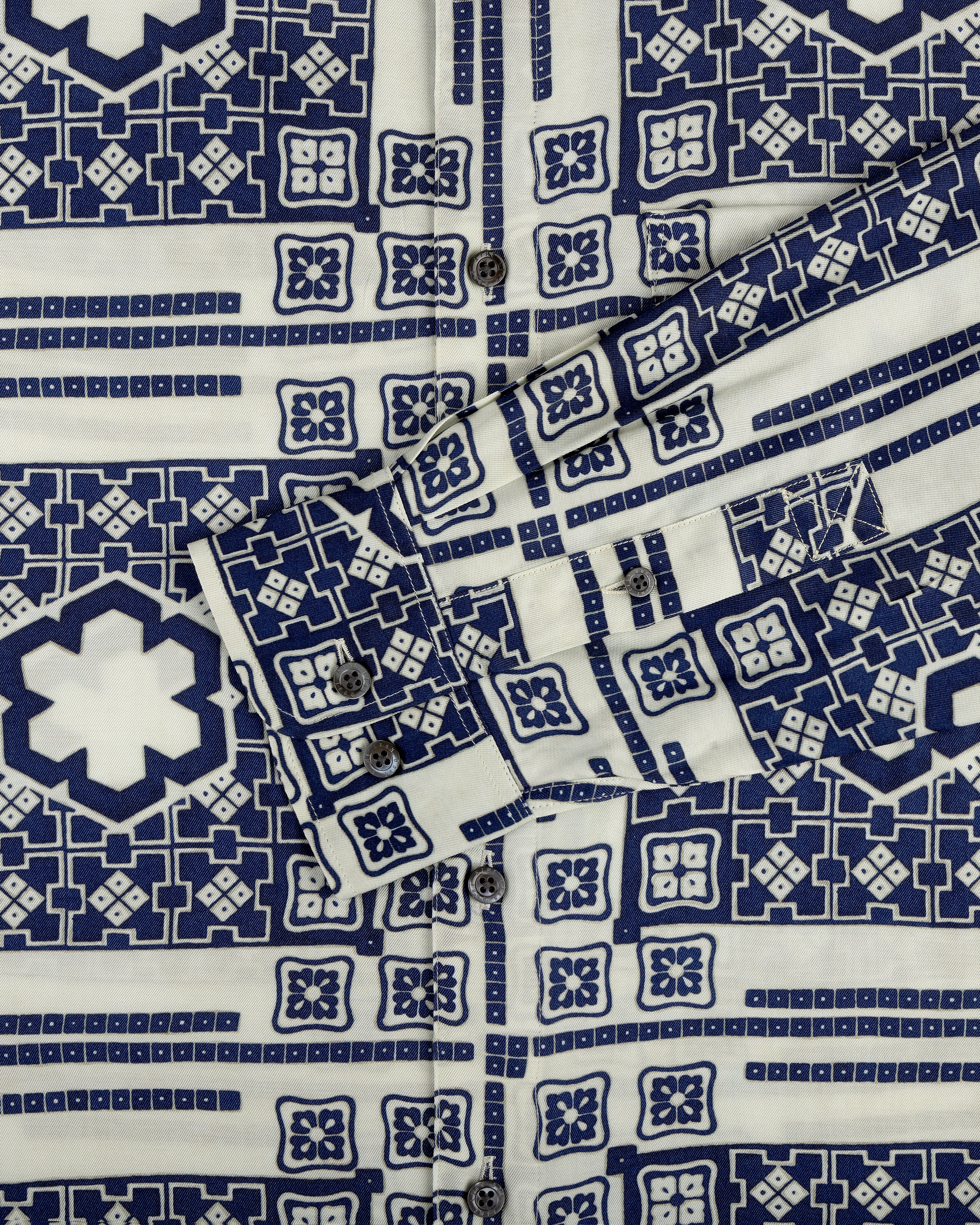 Close-up of the Mosaic Button Down Shirt with blue and white geometric patterns, buttons, and a folded cuff.
