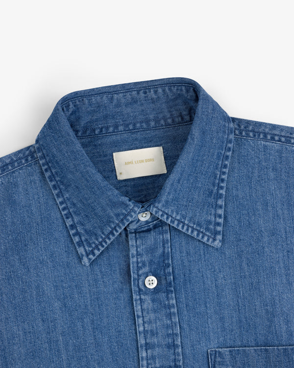 Crest Chambray Shirt: Blue denim button-up with a collar and a white neck label.