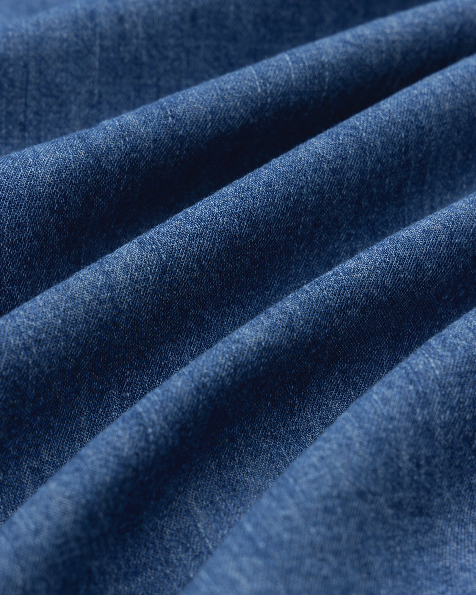 Close-up of Crest Chambray Shirt fabric, highlighting blue texture and diagonal ridges.
