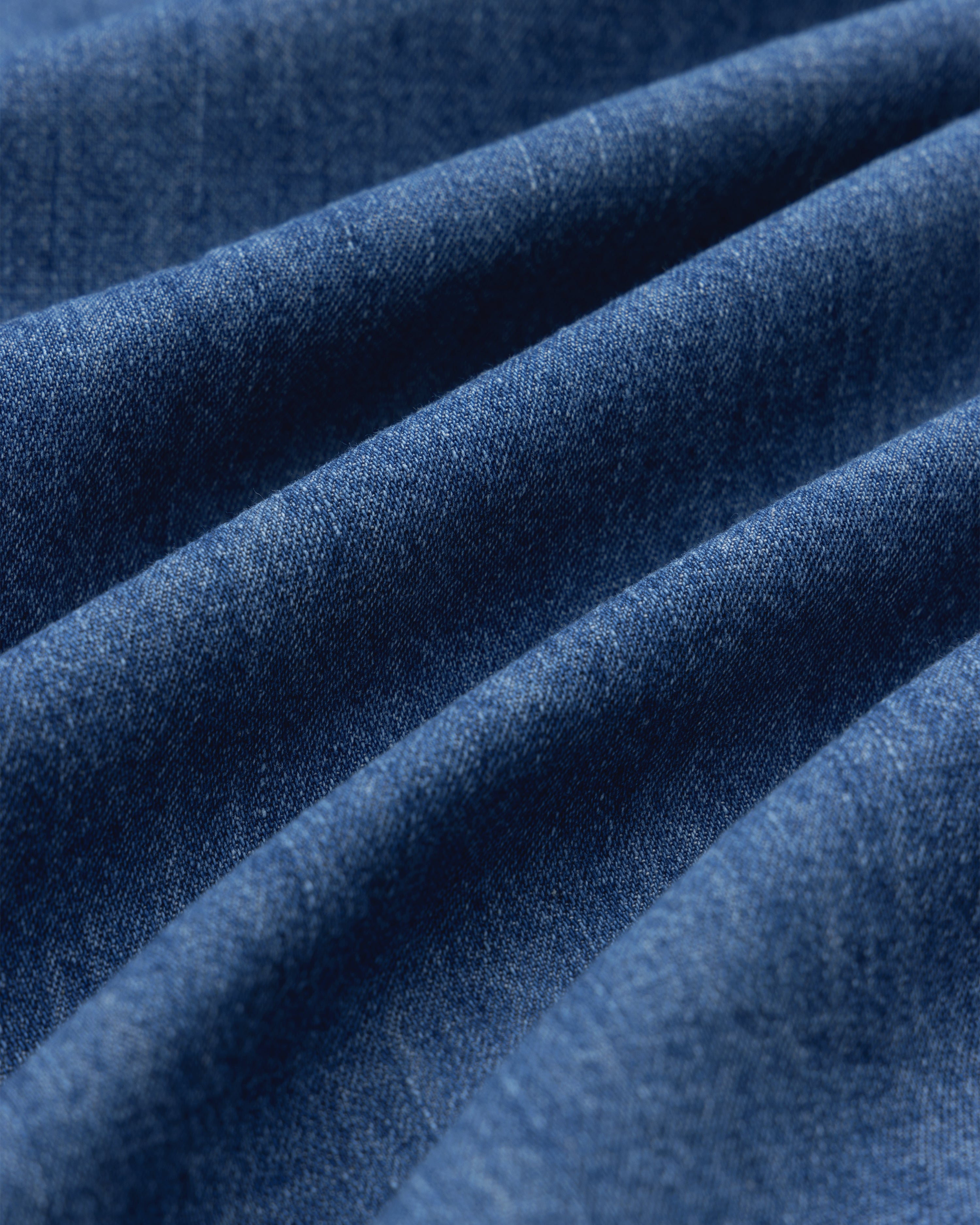 Close-up of Crest Chambray Shirt fabric, highlighting blue texture and diagonal ridges.