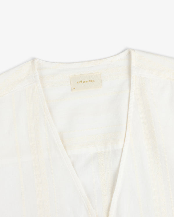 Close-up of the Jacquard Striped Tie-Front Shirt, cream-colored with subtle patterns and a beige Aimé Leon Dore label.