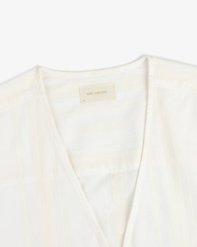 Close-up of the Jacquard Striped Tie-Front Shirt, cream-colored with subtle patterns and a beige Aimé Leon Dore label.