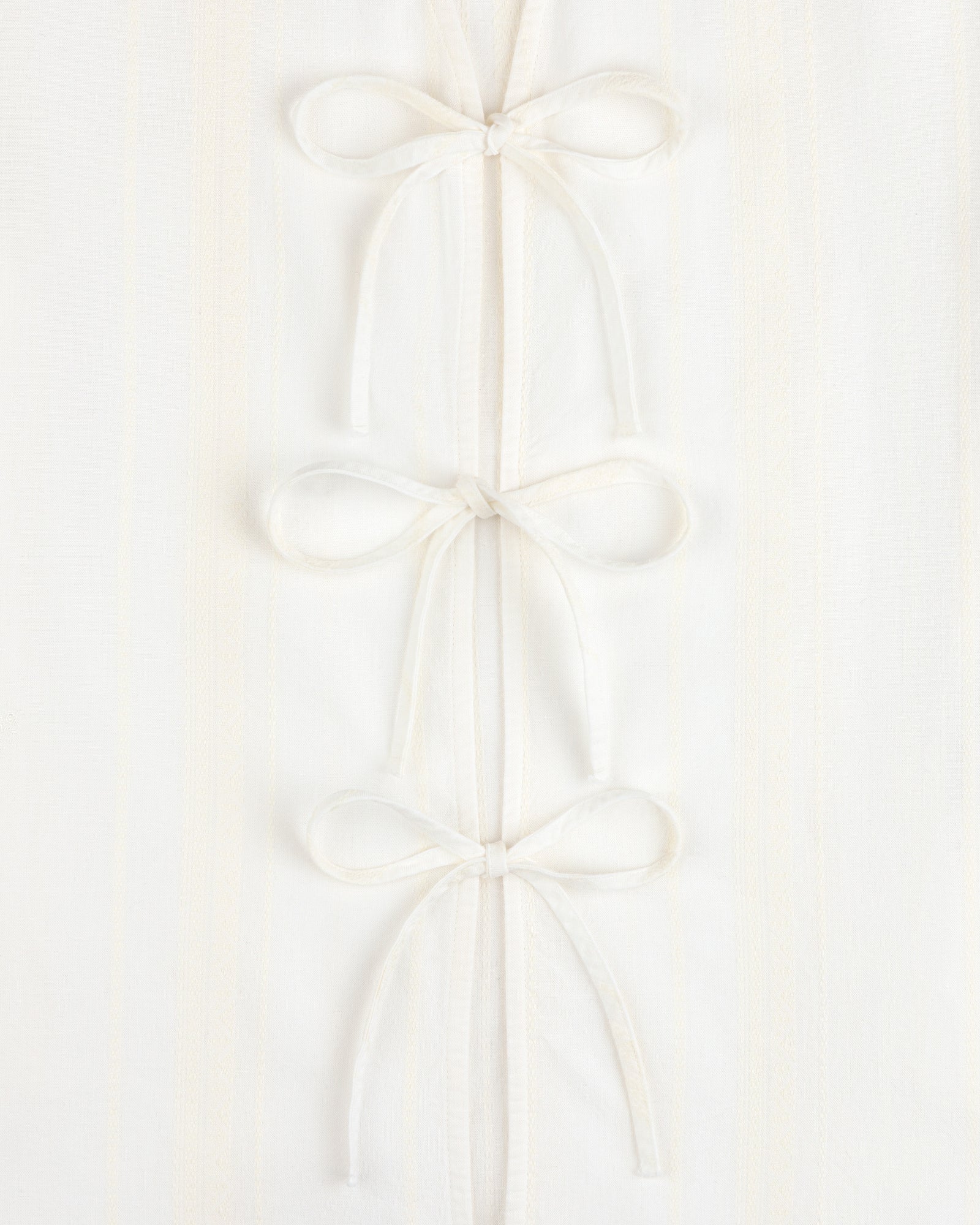 Jacquard Striped Tie-Front Shirt in white, featuring three fabric bows on a subtly striped background.