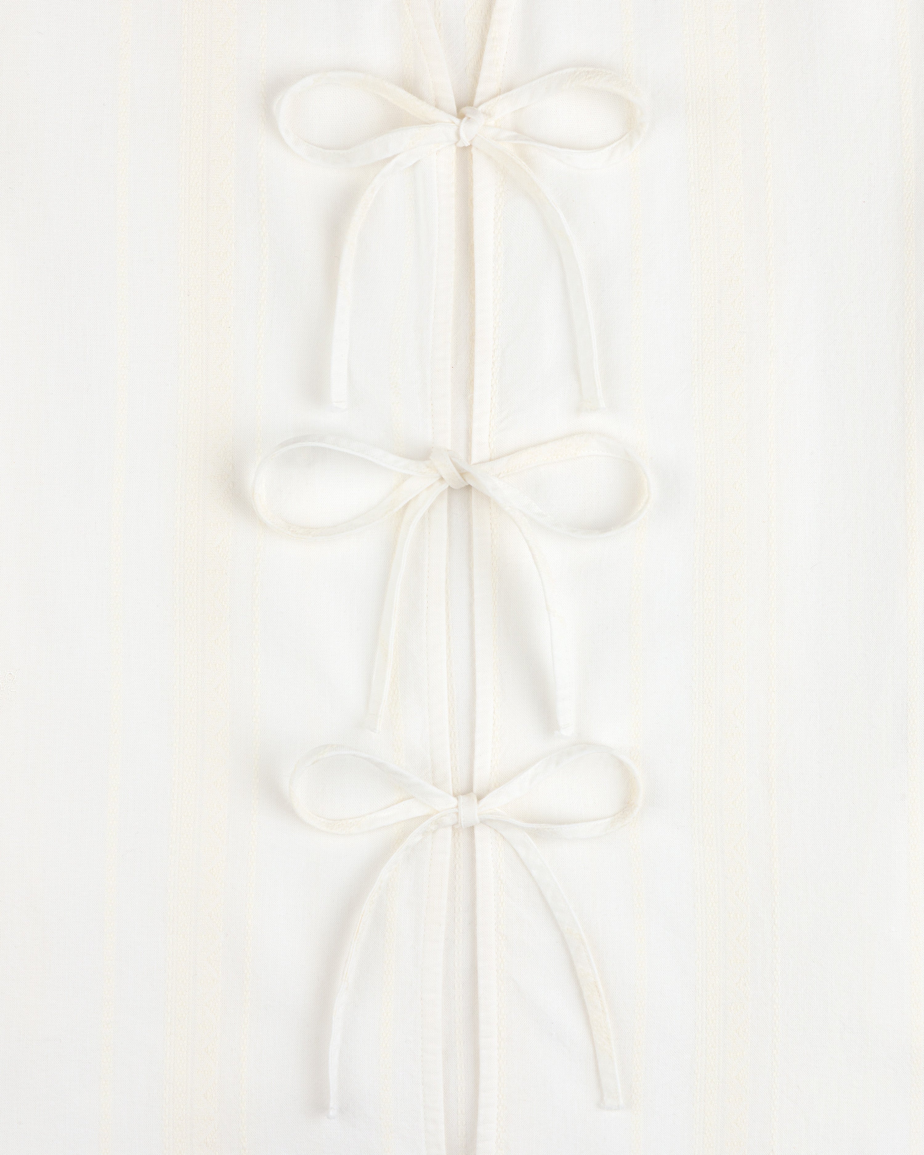 Jacquard Striped Tie-Front Shirt in white, featuring three fabric bows on a subtly striped background.