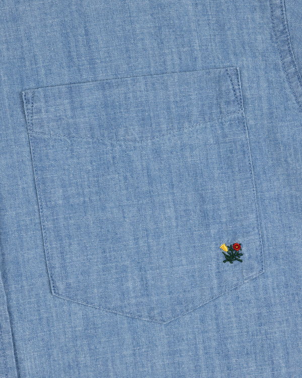 Close-up of the Crest Chambray Shirt’s blue denim pocket with yellow and red flower embroidery at the bottom right.