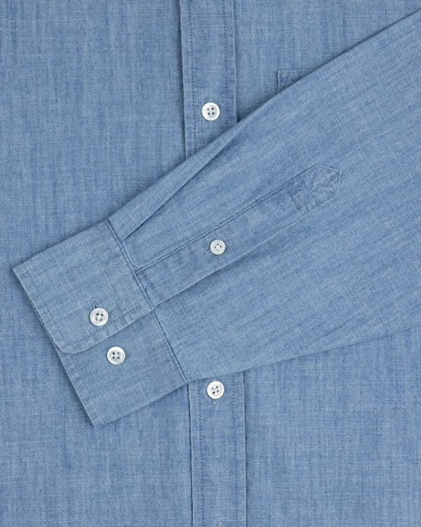 Crest Chambray Shirt in light blue with white buttons, featuring long sleeves laid flat across the front.