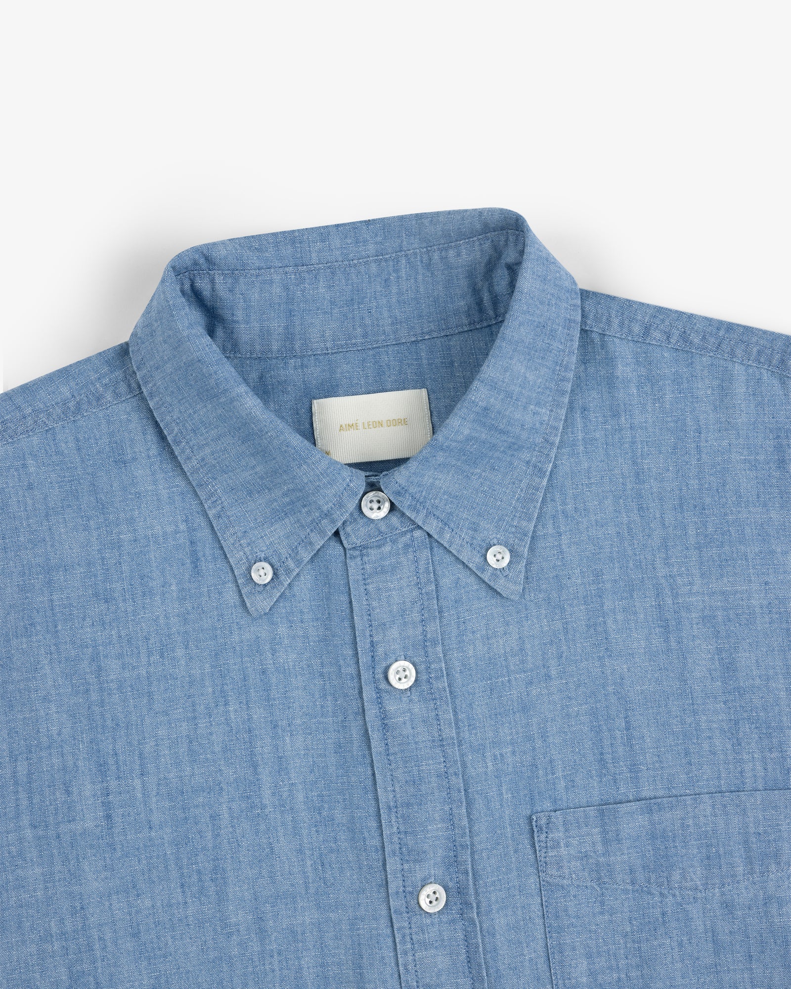 Crest Chambray Shirt in light blue, collared with chest pocket, shown from neck to mid-torso.