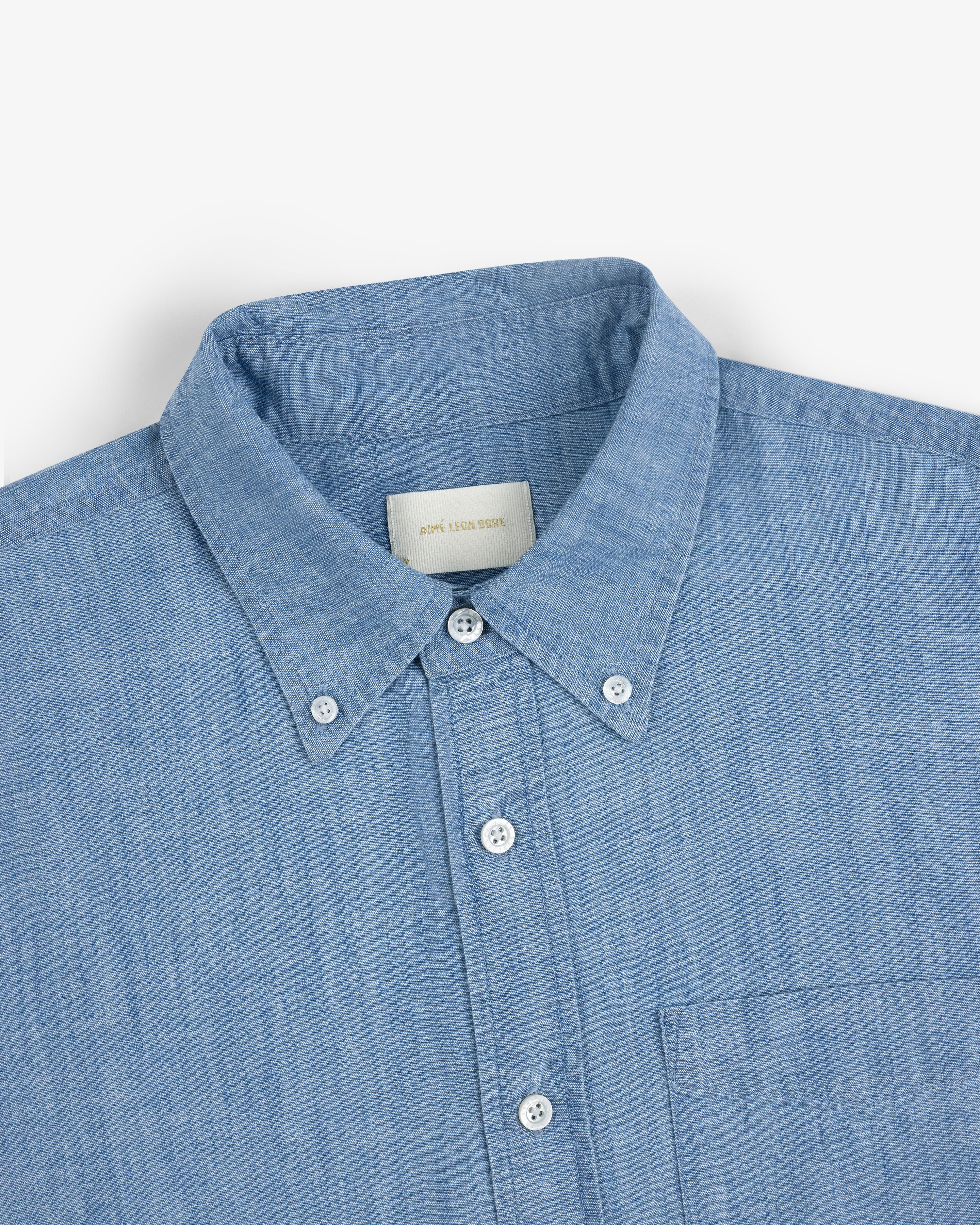 Crest Chambray Shirt in light blue, collared with chest pocket, shown from neck to mid-torso.
