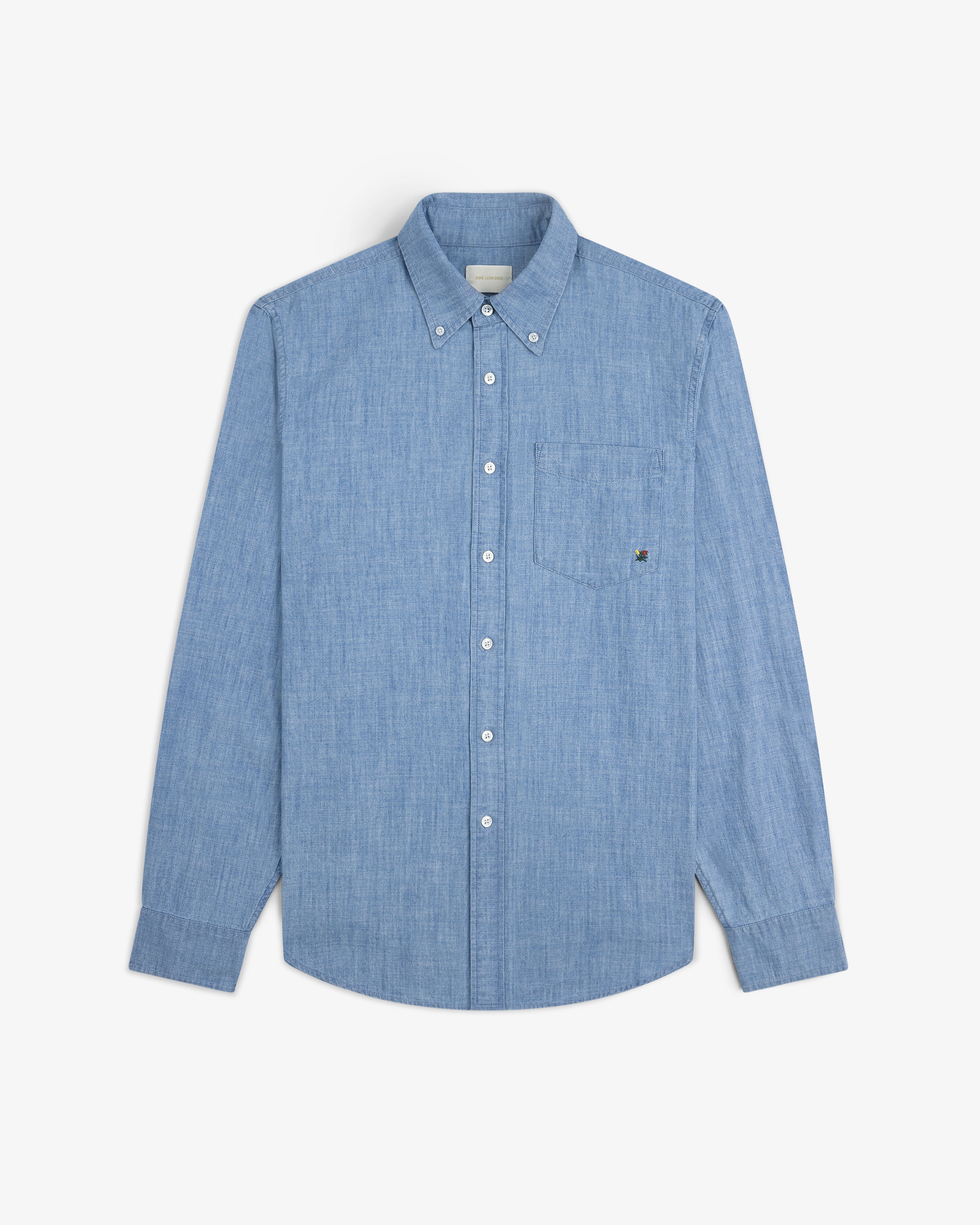 Crest Chambray Shirt: light blue long-sleeve button-up with chest pocket, shown on a white background.