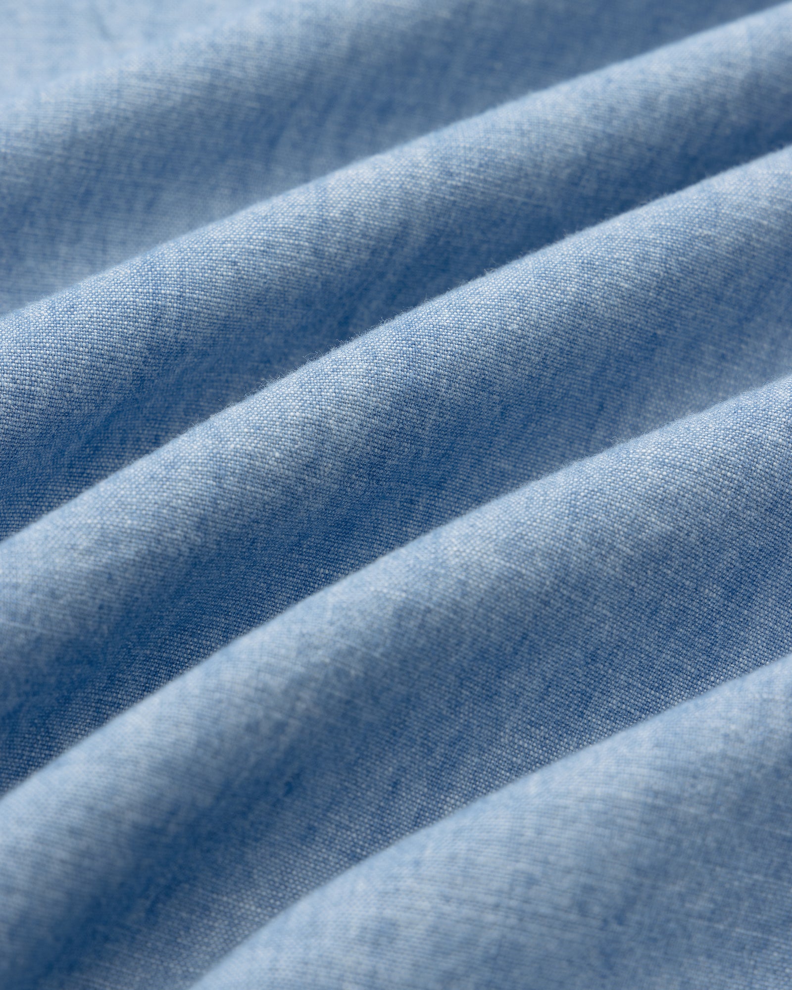 Close-up of Crest Chambray Shirt’s light blue fabric with soft, evenly spaced folds creating gentle texture.