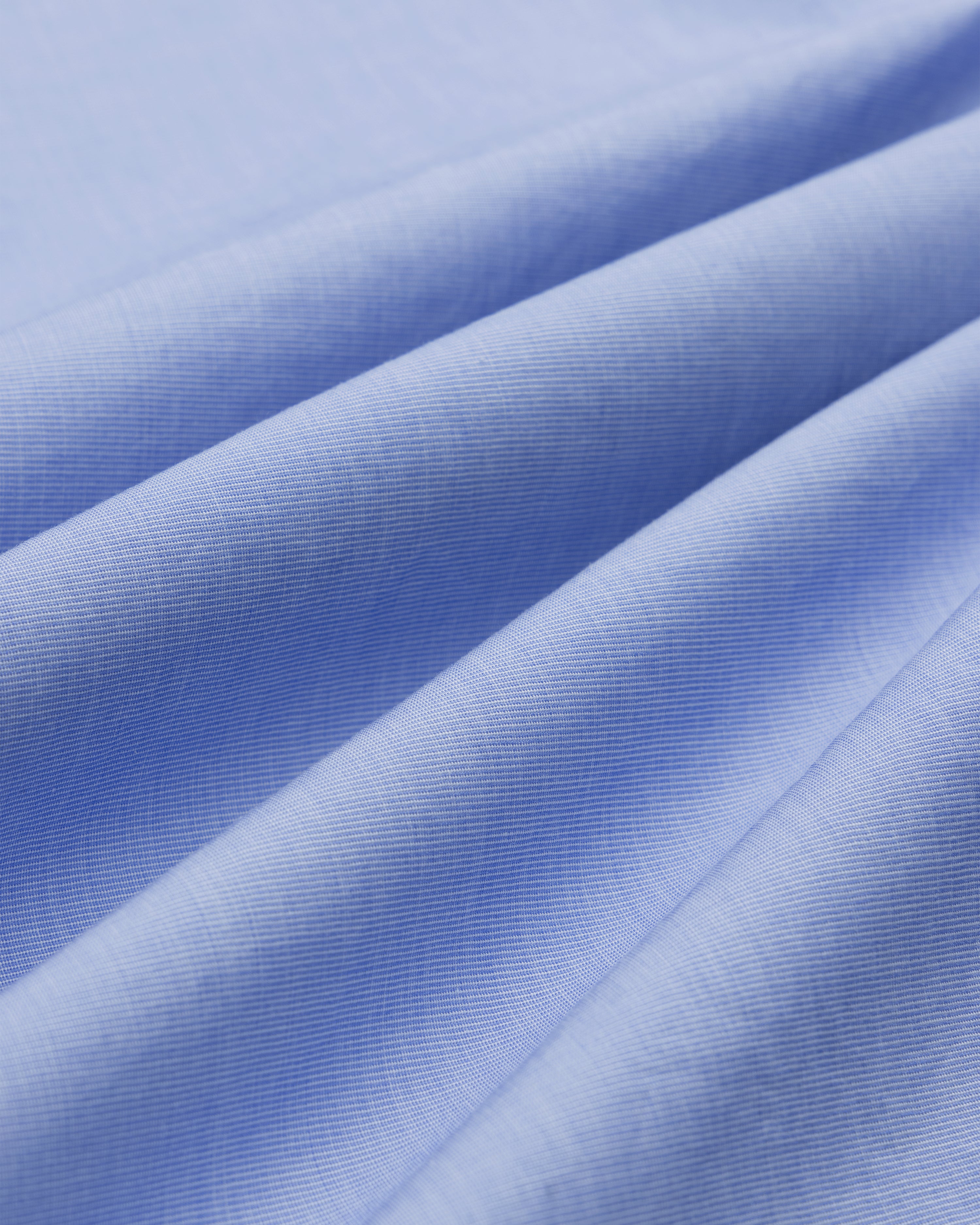 Close-up of Poplin Casual Shirt fabric in light blue, showing visible fibers, soft folds, and smooth texture.