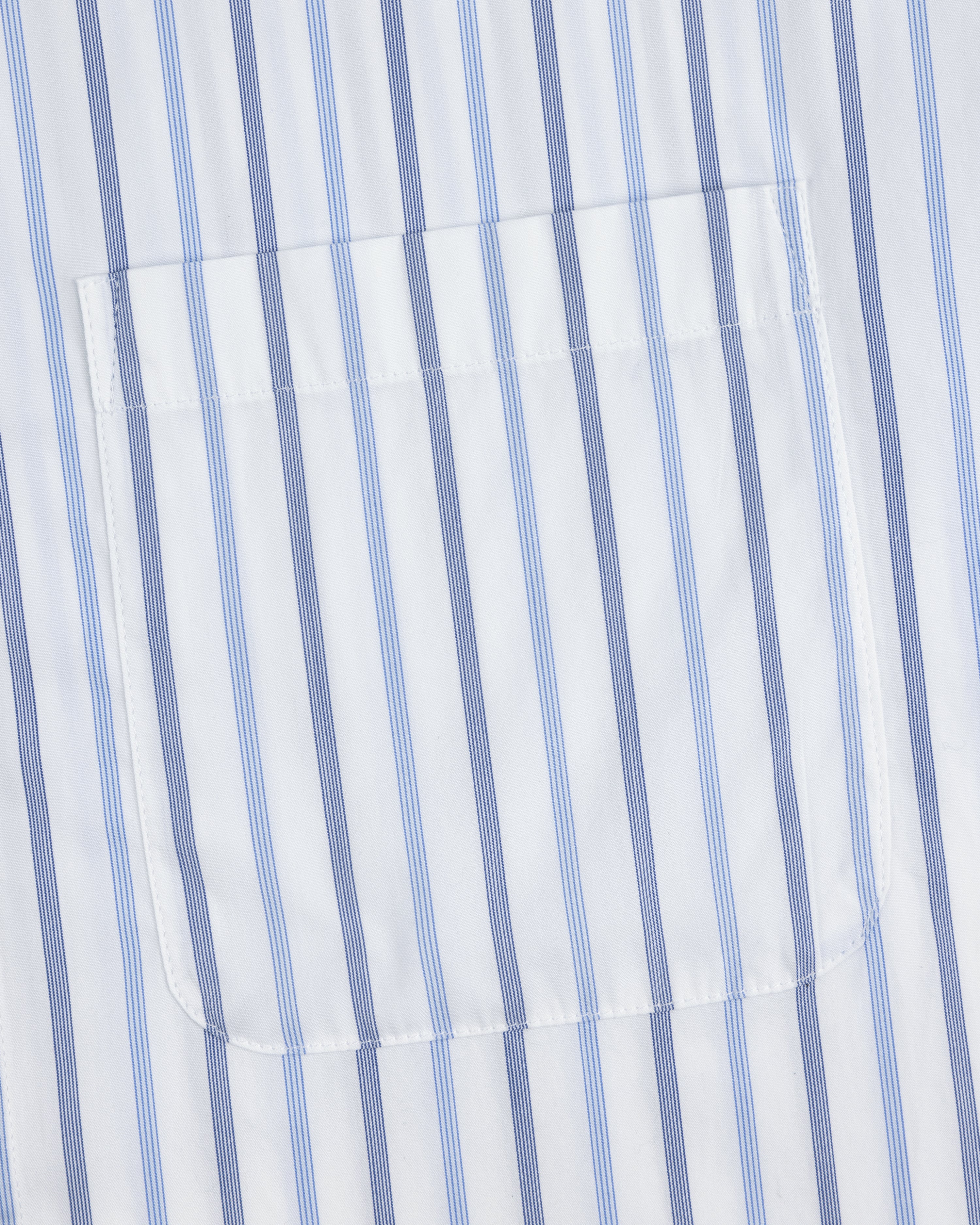 A close-up of the pocket on a Poplin Casual Shirt with vertical blue and light blue stripes on white fabric.