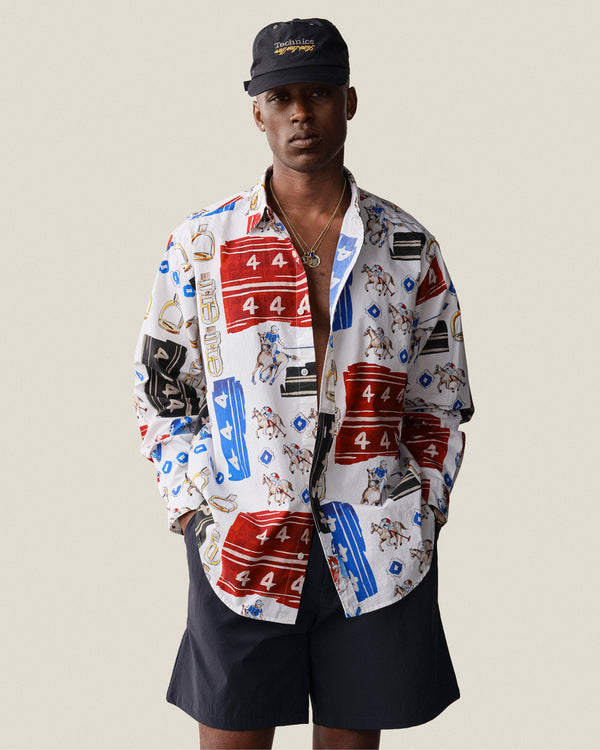 A man wears the Printed Leon Overshirt, black shorts, and a black cap against a plain background.