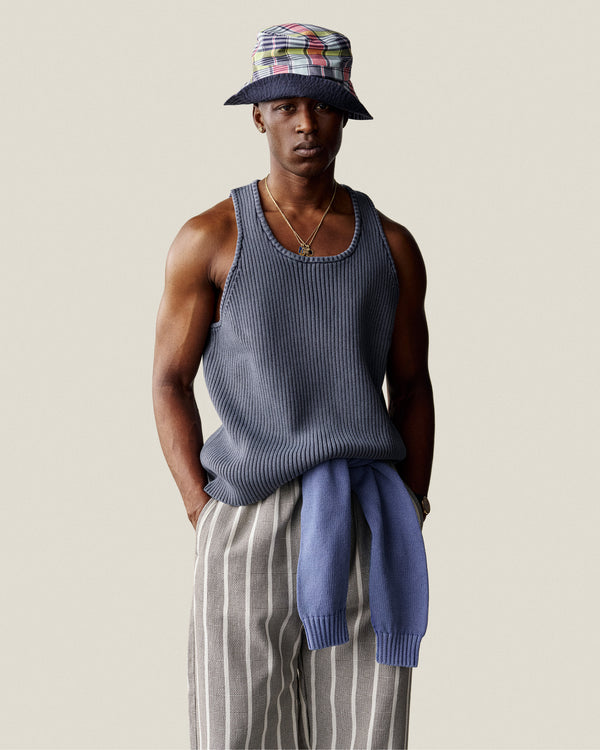 Man wearing a Stone Washed Knit Tank Top, striped pants, colorful bucket hat, and a sweater tied at his waist.