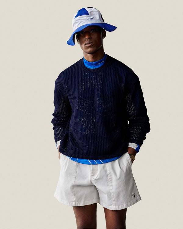 Someone wears the Fassianos Half-Zip Cycling Jersey, white shorts, and a blue-and-white bucket hat against a plain backdrop.