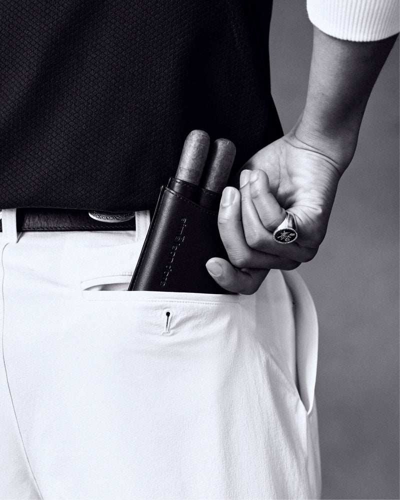 Someone slips the ALD Golf Leather Cigar Case holding two cigars into the pocket of white trousers.
