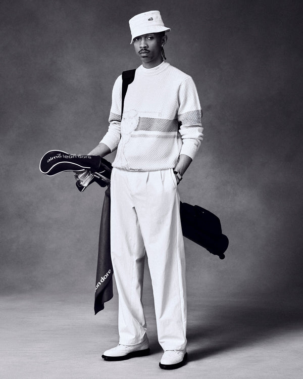 A man in white poses with the ALD Golf Driver Cover and clubs against a dark studio backdrop.
