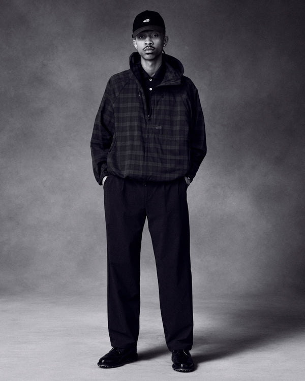 A man wearing the ALD Golf Lightweight Tips Windbreaker, black pants, shoes, and cap stands with hands in pockets.