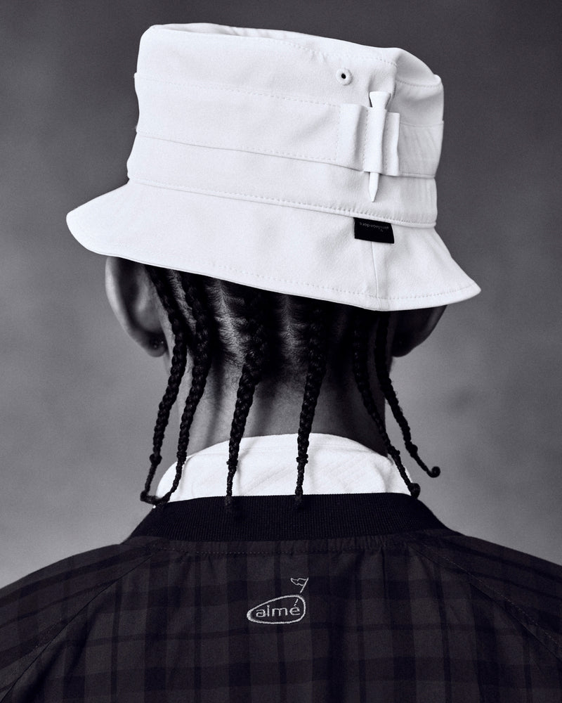Person with braided hair in an ALD Golf Bucket Hat and dark jacket, shown from behind against a plain background.