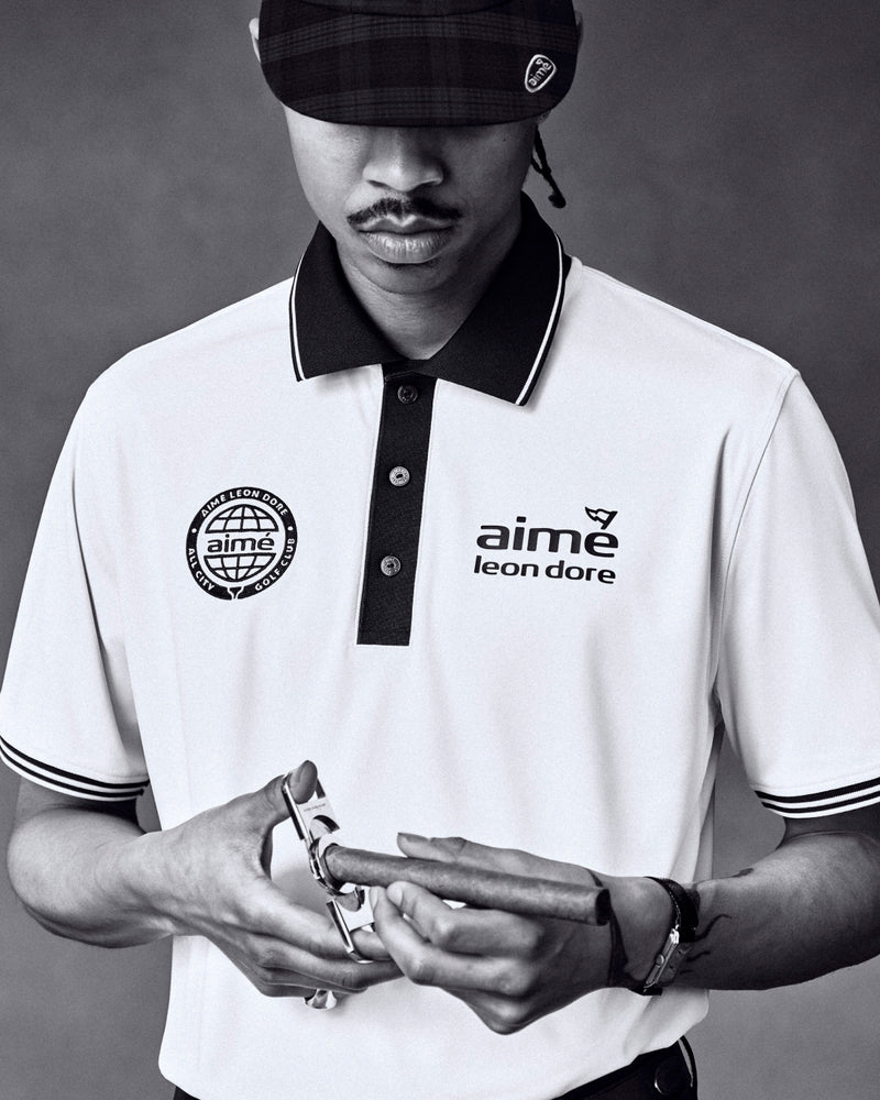 Black and white photo of a man in an ALD Golf Tour Polo, looking down and holding a watch.