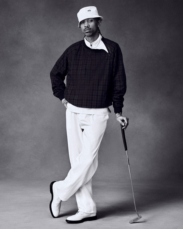 Someone poses in the ALD Golf Blackwatch Pullover with a golf club, wearing golf attire and a bucket hat.