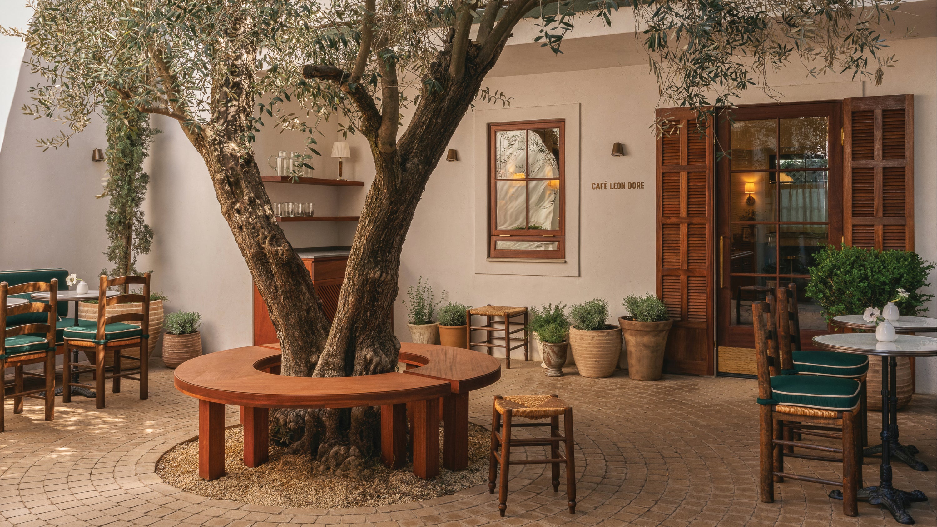 Outdoor seating area with a large tree in the center of a restaurant.