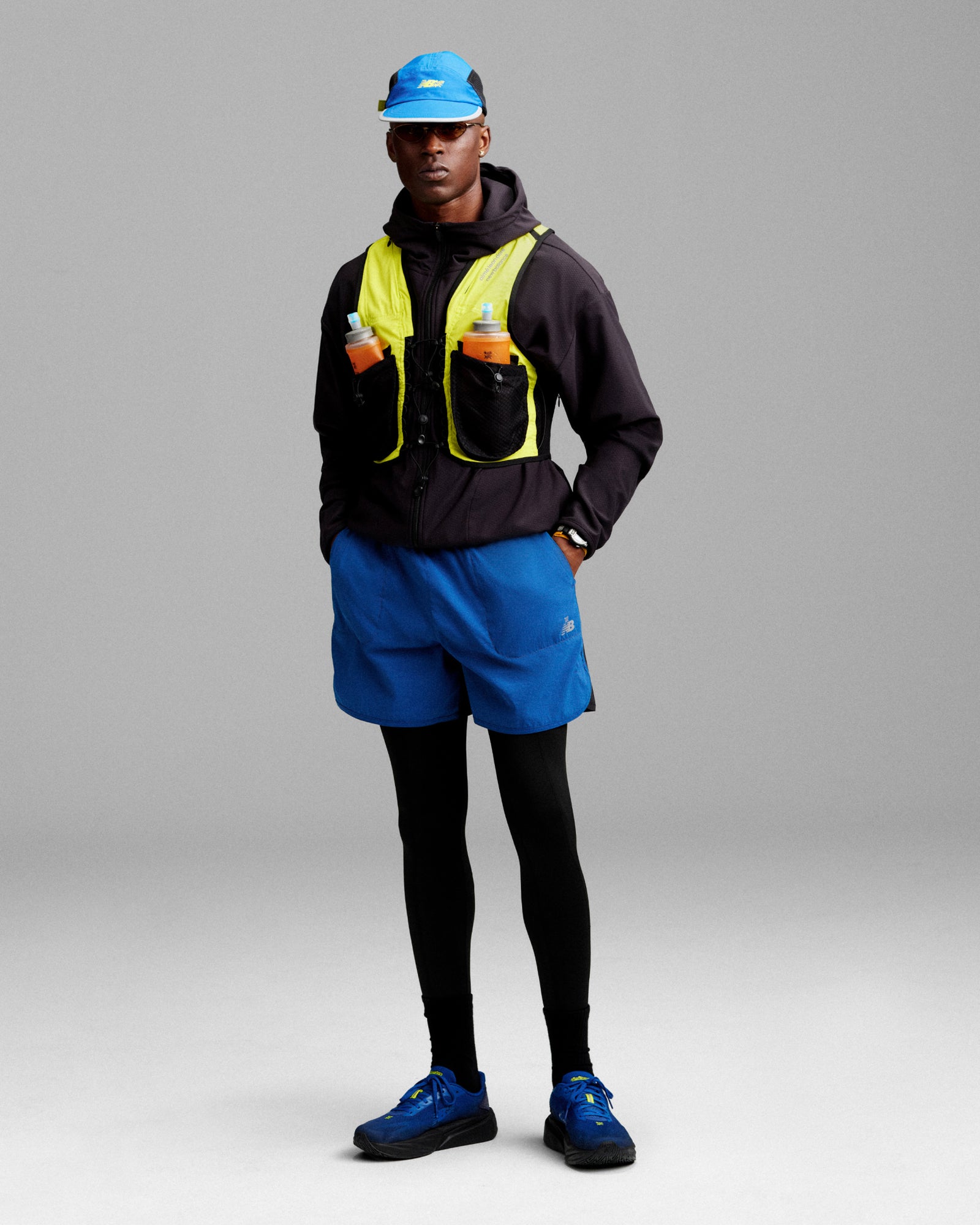 A person wearing the ALD / New Balance Performance Lightweight Running Short and running gear stands against a gray background.