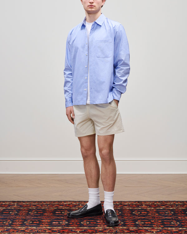 Someone in a Poplin Casual Shirt, beige shorts, white socks, and black loafers stands on a patterned rug.