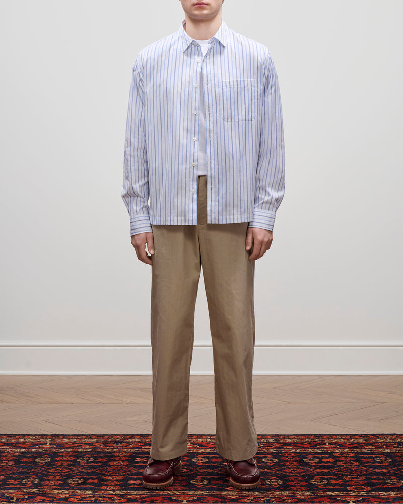 A person stands on a patterned rug wearing tan pants, brown shoes, and the Poplin Casual Shirt against a plain background.