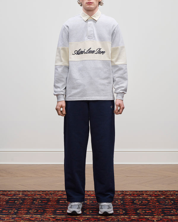 Person wearing the Script Paneled Rugby, navy pants, and grey sneakers, standing indoors.