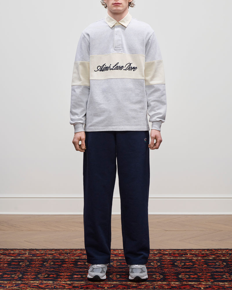 Person wearing the Script Paneled Rugby, navy pants, and grey sneakers, standing indoors.