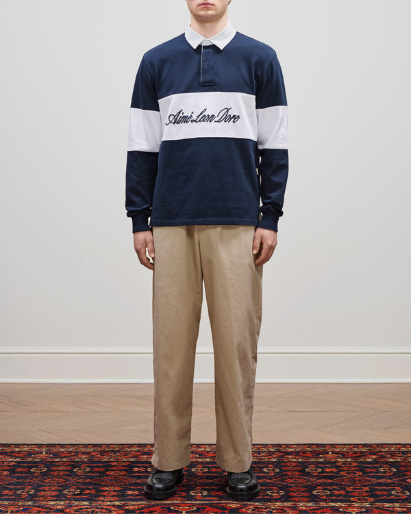 A person wears the Aimé Leon Dore Script Paneled Rugby shirt, khaki pants, and black shoes.