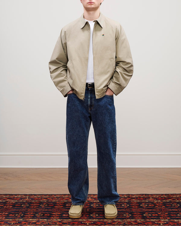 A person in a Crest Casual Jacket, white t-shirt, blue jeans, and tan shoes stands on a patterned rug.